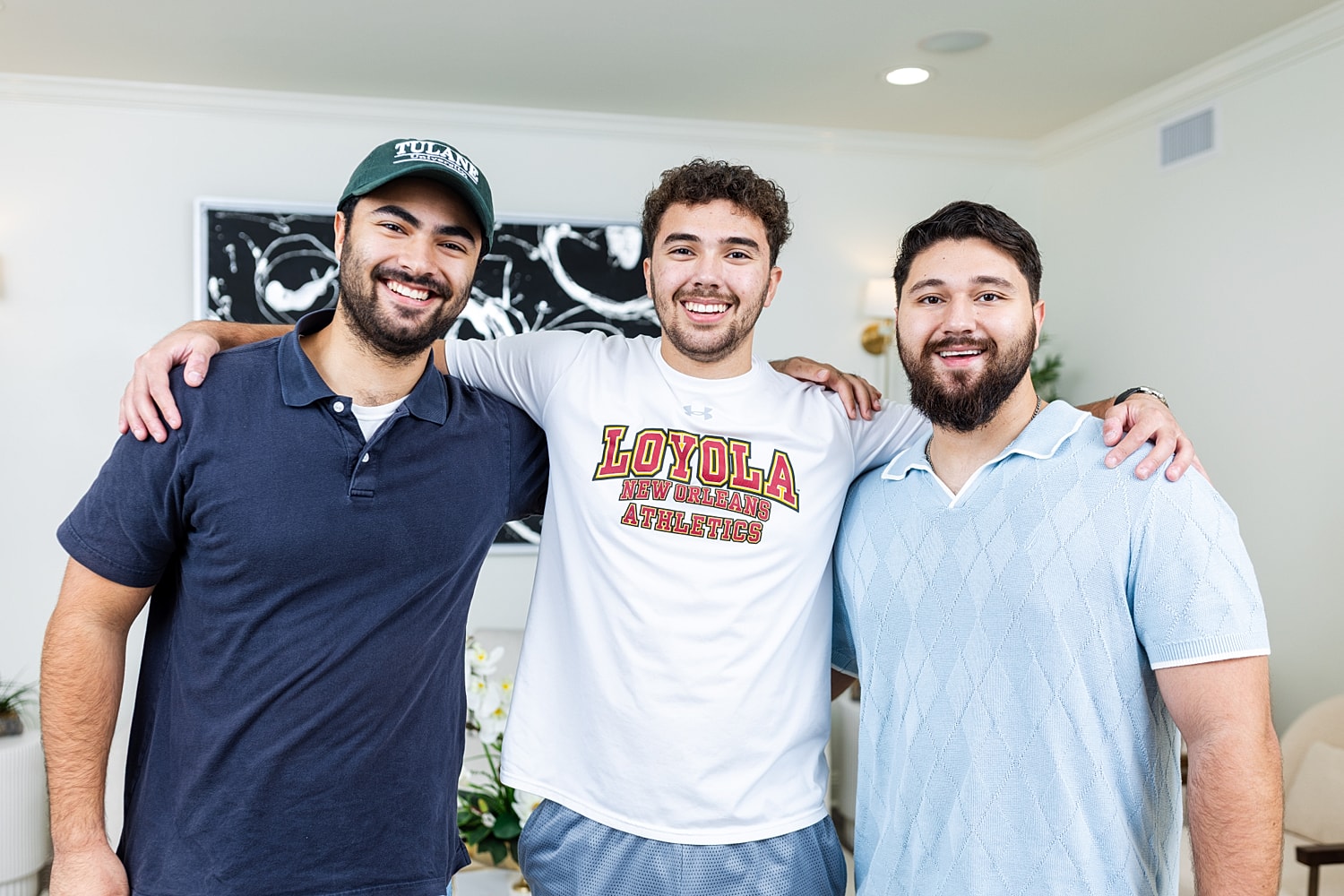 Three friends smiling together indoors.