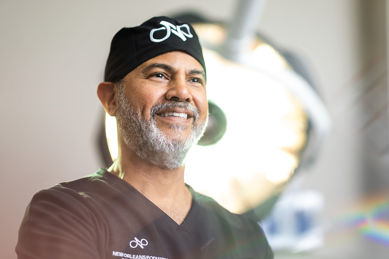 Smiling surgeon in scrubs with medical lighting.