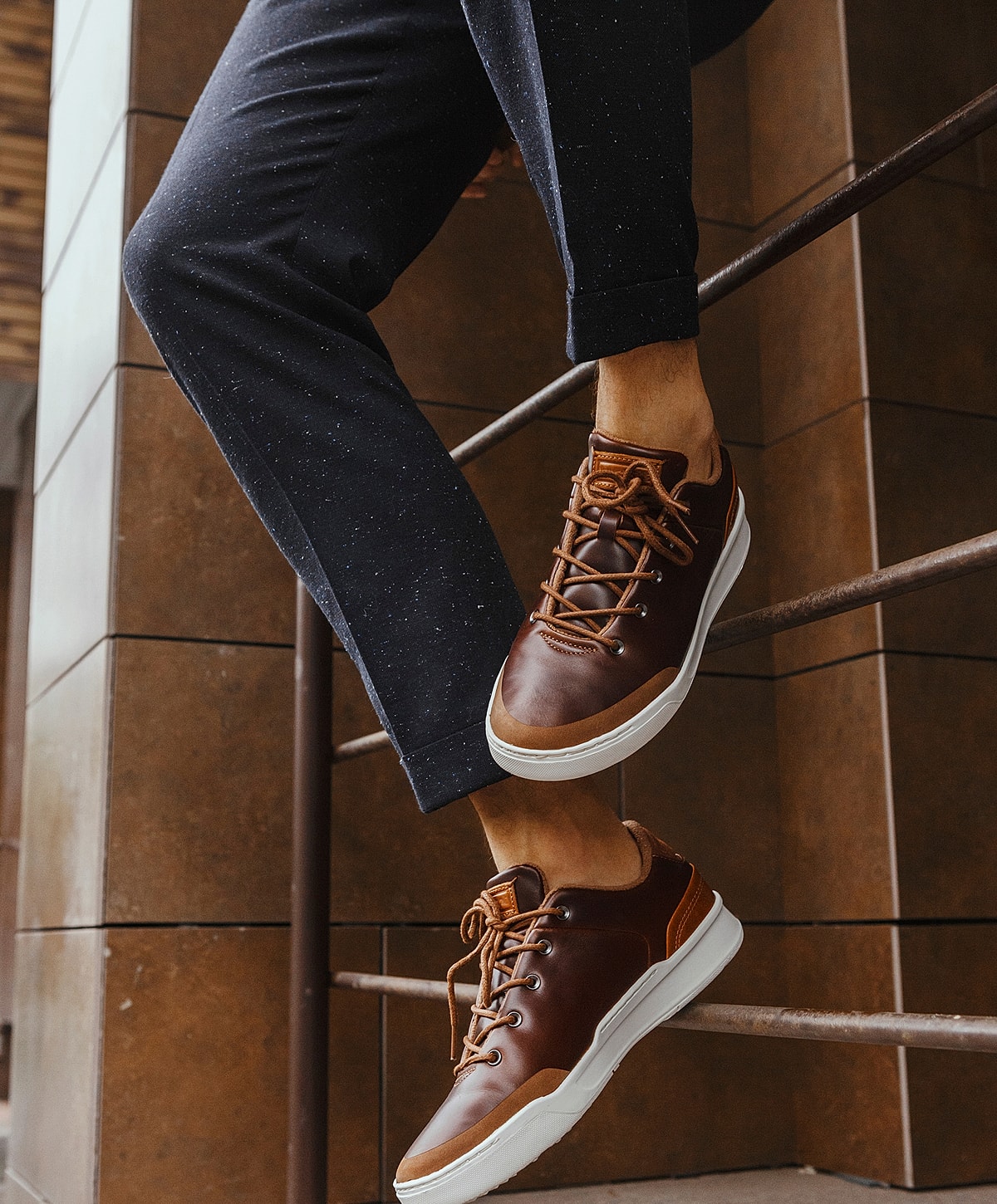 Brown sneakers worn with dark pants.