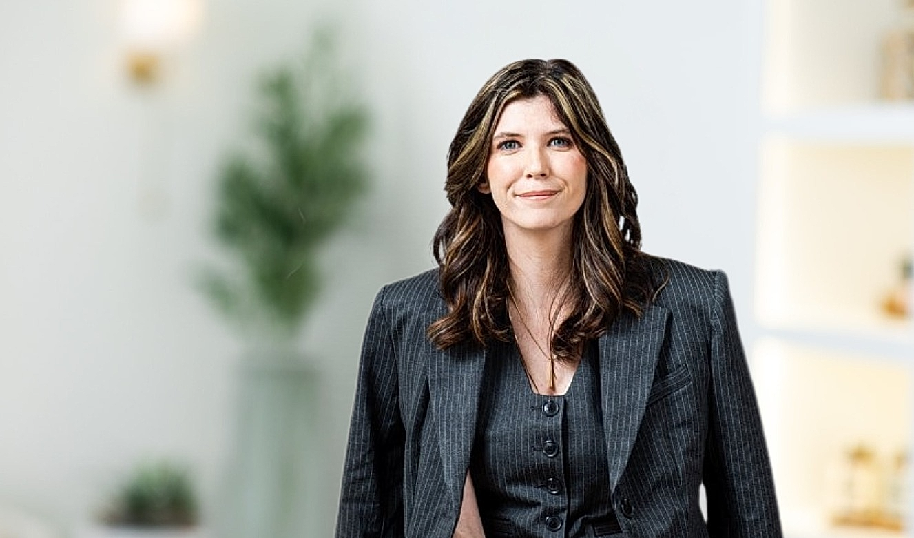 Businesswoman in a tailored dark suit, smiling.