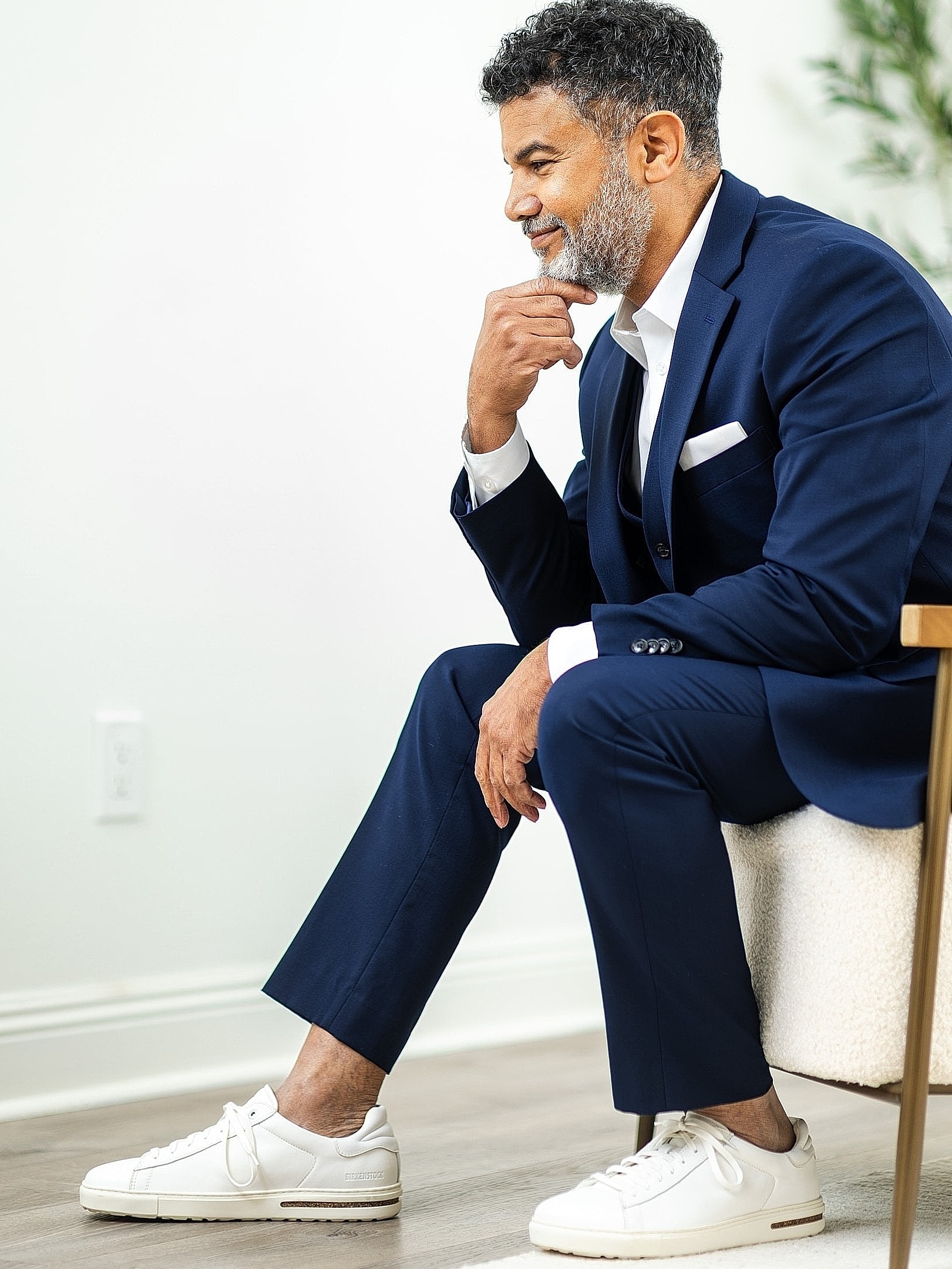 Man in suit and sneakers, deep in thought.