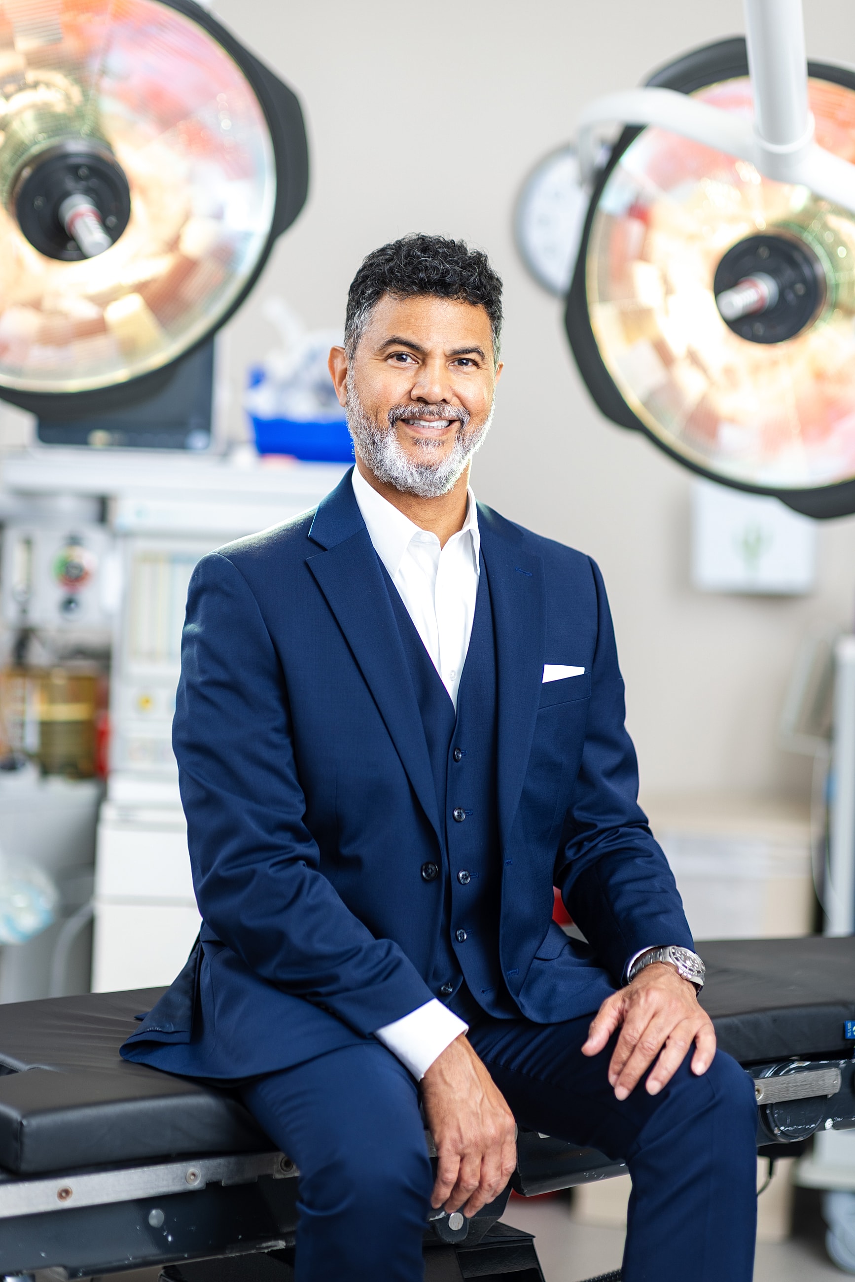 Smiling man in suit, surgical lights background.