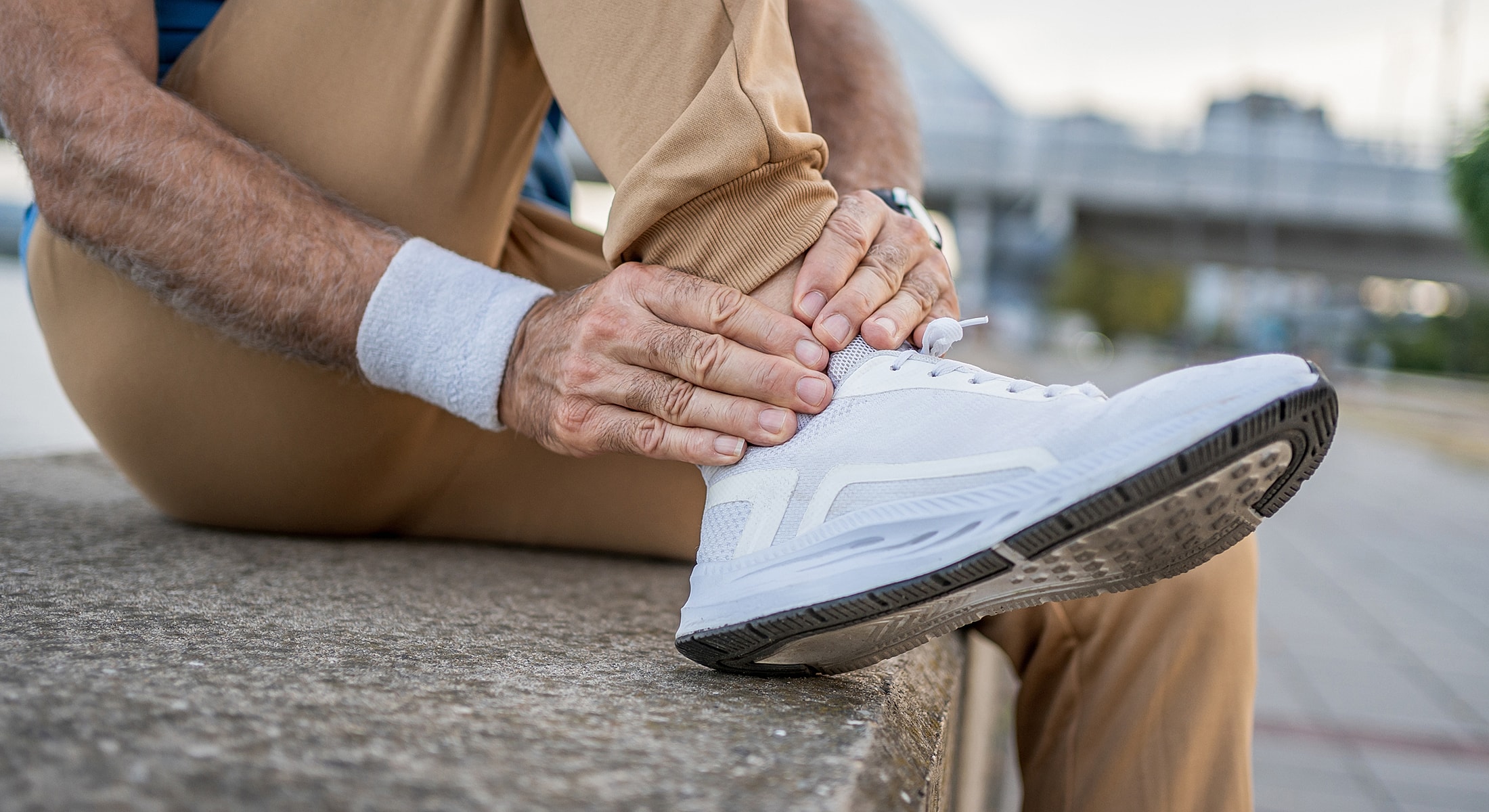 Person experiencing ankle pain while sitting.