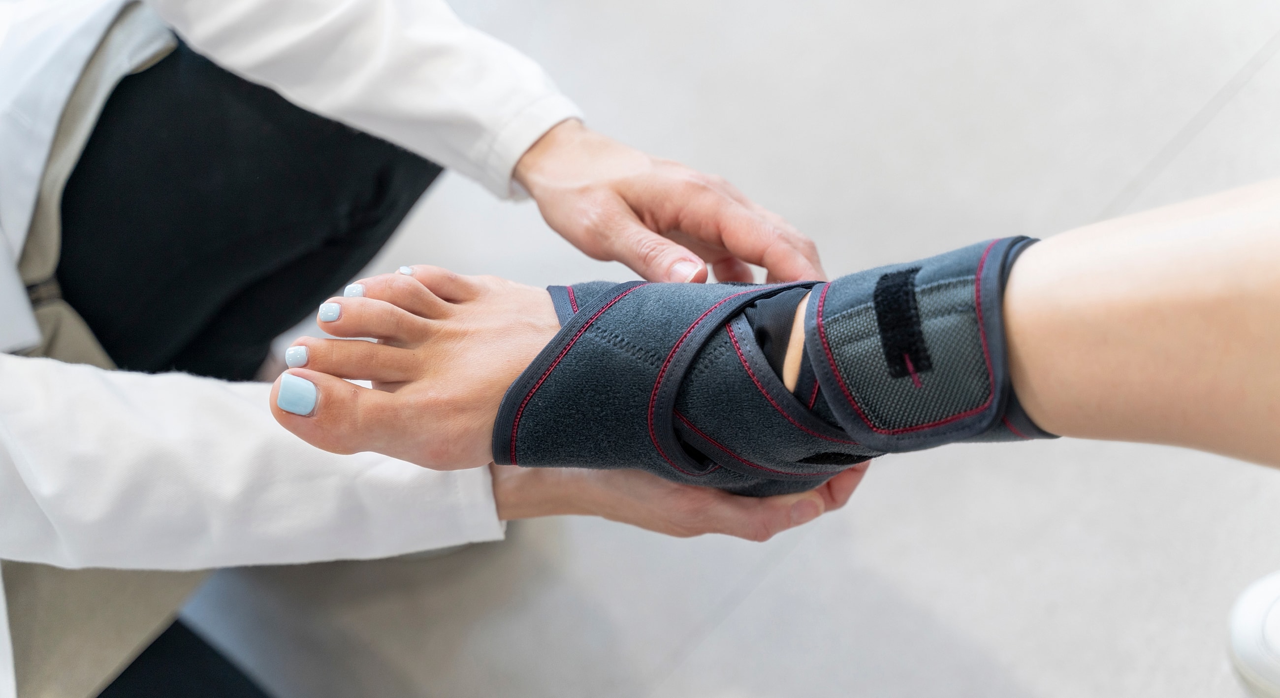 Medical professional adjusting ankle brace on foot.