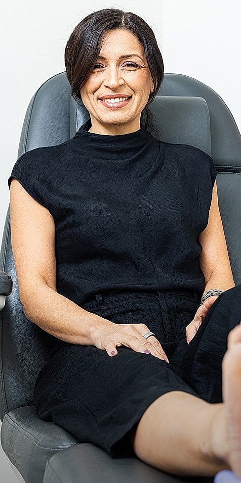 Smiling woman at footcare appointment, relaxed setting.
