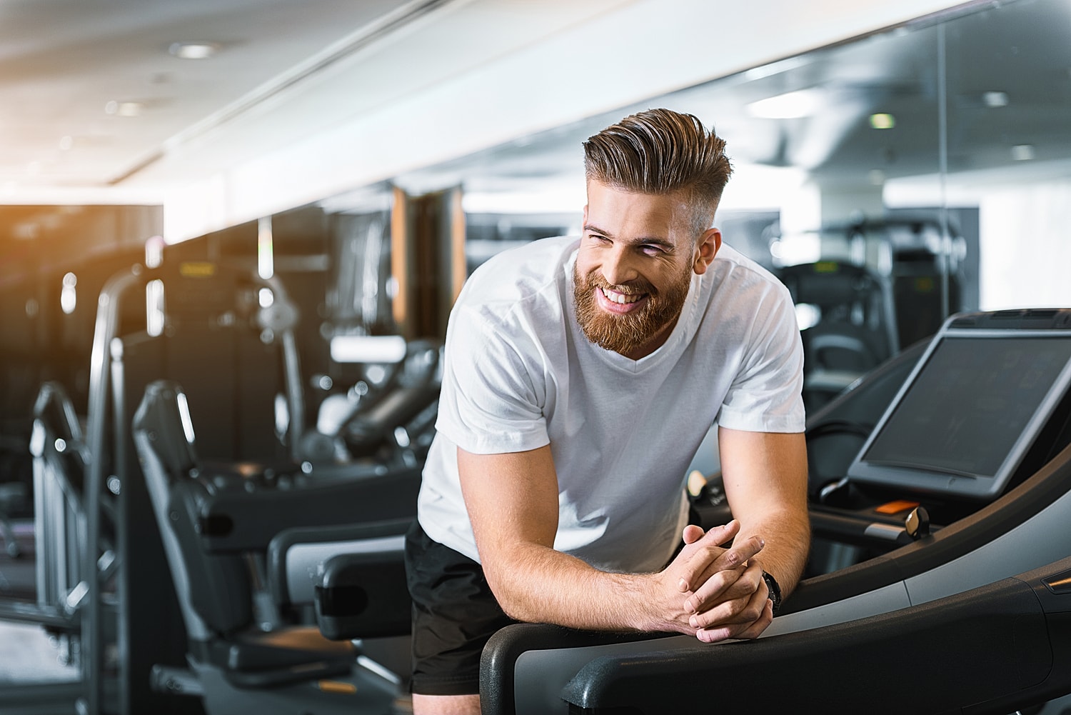 Smiling man at gym equipment, fitness motivation.